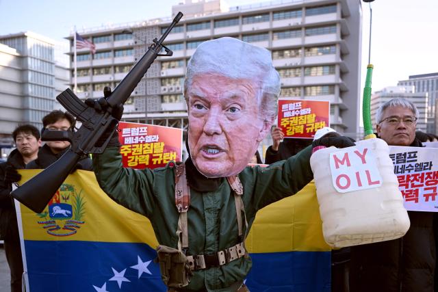 A protester wearing a mask of US President Donald Trump performs during a demonstration condemning the US attack on Venezuela and the seizure of Venezuelan leader Nicolas Maduro, in front of the US embassy in Seoul on January 5, 2026. (Photo by Jung Yeon-je / AFP)