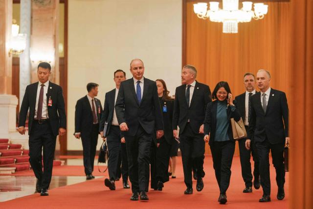 Ireland's Prime Minister Micheal Martin (C) walks with his delegations as they arrive at the Great Hall of the People to meet with China's President Xi Jinping in Beijing on January 5, 2026. (Photo by Andy Wong / POOL / AFP)