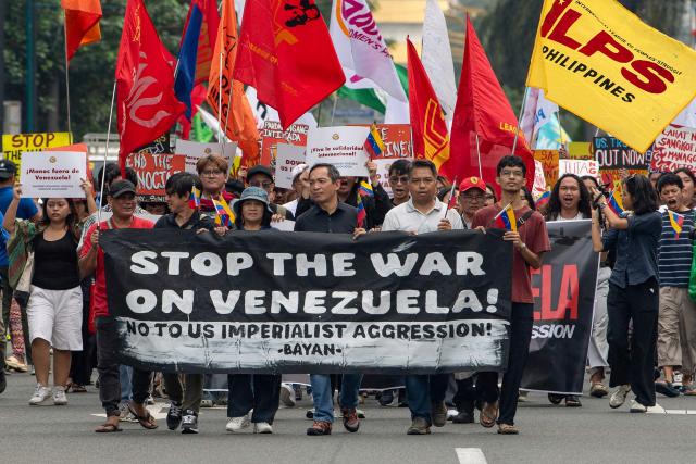 Protesters with flags and and a banner march during a demonstration condemning the US attack on Venezuela and the seizure of Venezuelan leader Nicolas Maduro, near the US embassy in Manila on January 5, 2026. (Photo by Ted ALJIBE / AFP)
