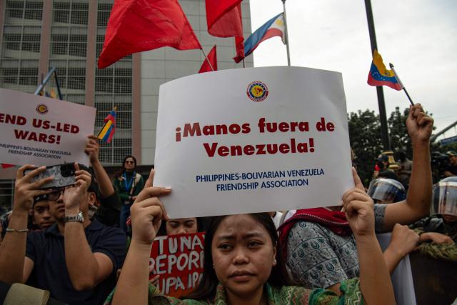 A protester holds a placard reading "Hands off Venezuela" during a demonstration condemning the US attack on Venezuela and the seizure of Venezuelan leader Nicolas Maduro, near the US embassy in Manila on January 5, 2026. (Photo by Ted ALJIBE / AFP)