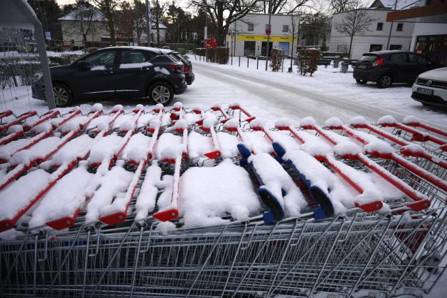 Shopping carts are covered with snow in front of a closed supermarket in Berlin's Schlachtensee district on January 5, 2026, on the third day of a power outage which left tens of thousands of households in the German capital without electricity. Police in Berlin said they suspected the far-left Volcano Group of being behind an arson attack that has left tens of thousands of homes in the German capital without power. Early on Saturday morning (January 3, 2026) several high-voltage power cables were spotted in flames on a bridge near a power plant in the southwest of the city. The blaze was quickly put out, but about 45,500 households and 2,200 businesses were left without electricity. Stromnetz Berlin, which runs the city's electricity network, said that it would take until Thursday, January 8, 2026 to reconnect all customers, with freezing temperatures slowing the repair work to the cables. (Photo by RALF HIRSCHBERGER / AFP)