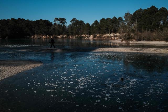 This photograph taken on January 5, 2026 shows the frozen Lac Bleu in Léognan, south-western France. The lake, located within an 18-hectare forest park south of Bordeaux, owes its name to the distinctive turquoise to azure color of its waters caused by limestone sediments that reflect light. (Photo by Philippe LOPEZ / AFP)
