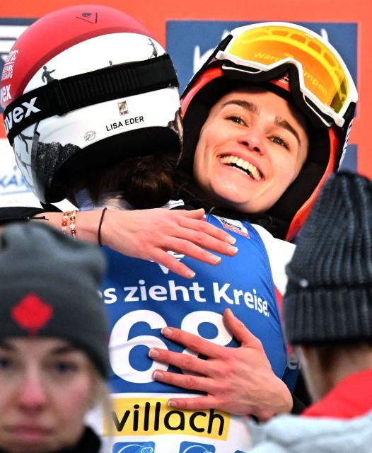 Second placed Austria's Lisa Eder and third placed Germany's Selina Freitag (R) embrace on the podium after the normal hill HS98 event of the women's FIS Ski Jumping World Cup in Villach, Austria on January 5, 2026. (Photo by BARBARA GINDL / APA / AFP) / Austria OUT