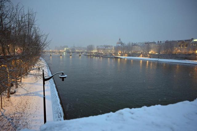 This photograph shows the Seine river and its banks covered in snow in Paris on January 5, 2026. (Photo by Christophe DELATTRE / AFP)