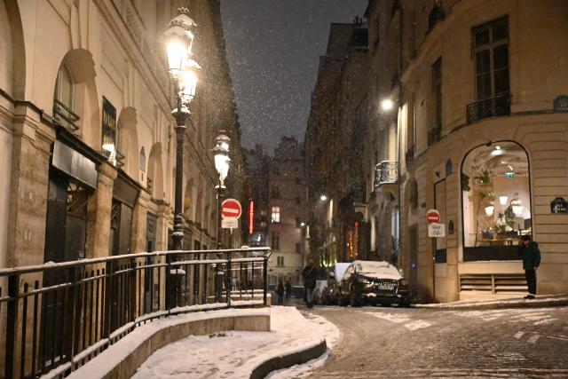 Pedestrians walk in a street covered in snow in Paris on January 5, 2026. (Photo by Christophe DELATTRE / AFP)