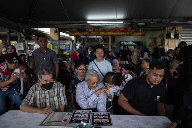(FILES) This picture taken on May 11, 2025 shows a woman giving a hand kiss to Malaysia's former Prime Minister Mahathir Mohamad (C) during his morning breakfast at a cafe in Puchong, on the outskirts of Kuala Lumpur. Malaysia's century-old former prime minister Mahathir Mohamad was brought to the hospital on January 6, 2026 after a fall at his residence, his aide told AFP. (Photo by Mohd RASFAN / AFP)