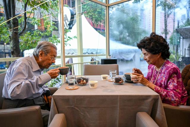 (FILES) This picture taken on June 15, 2025 shows Malaysia's former Prime Minister Mahathir Mohamad and his wife Hasmah Mohamad Ali drinking coffee at an ice cream shop in Shah Alam, on the outskirts of Kuala Lumpur. Malaysia's century-old former prime minister Mahathir Mohamad was brought to the hospital on January 6, 2026 after a fall at his residence, his aide told AFP. (Photo by Mohd RASFAN / AFP)