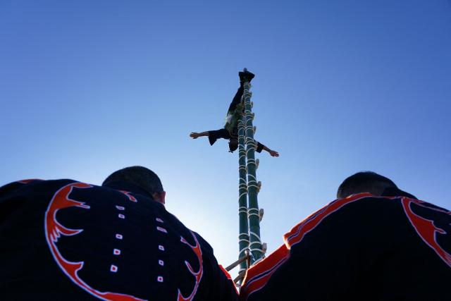 A member of the Edo Firemanship Preservation Association performs acrobatic atop ladders at the Tokyo Fire Department’s New Year fire brigades exercise in Tokyo on January 6, 2026. (Photo by Kazuhiro NOGI / AFP)