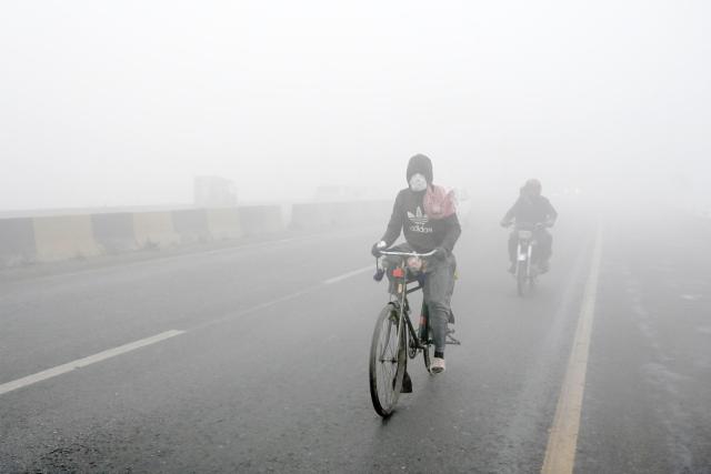 Commuters ride their bikes amid dense fog on a winter morning in Peshawar on January 6, 2026. (Photo by Abdul Majeed AFP photographer / AFP)