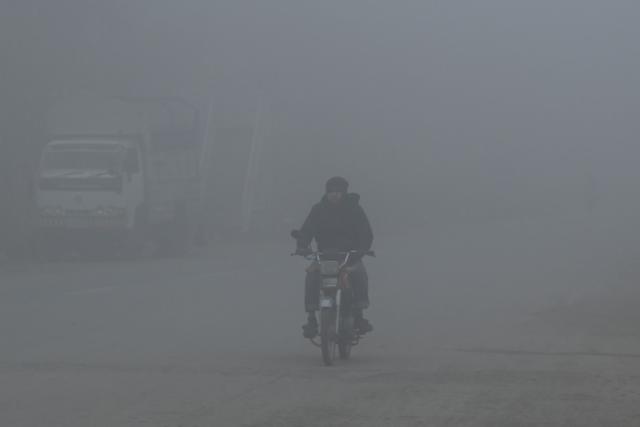 A motorist rides his bike amid dense fog on a winter morning in Islamabad on January 6, 2026. (Photo by Farooq NAEEM / AFP)