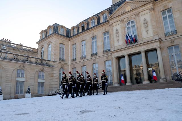 French Republican Guards walk on the snow-covered courtyard after French president's meeting with Canadaian Prime Minister at the Elysee Palace in Paris, on January 6, 2026, prior to the Coalition of the Willing summit on security guarantees for Ukraine. The summit of the group of Ukraine supporters dubbed the "Coalition of the Willing" is the latest of several meetings planned for the new year as diplomatic efforts to end Europe's deadliest conflict since World War II have gained pace in recent weeks. (Photo by Ludovic MARIN / AFP)