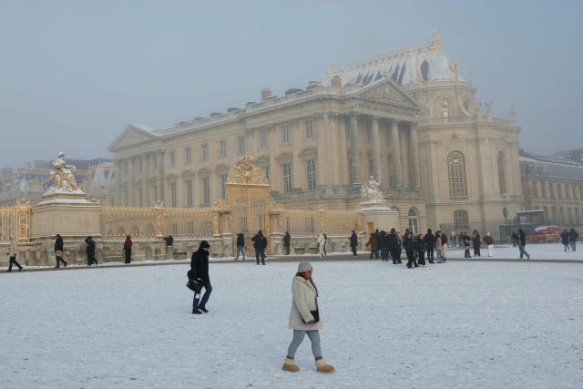 Visitors past the Chateai de Versailles blanketed in snow, in Versailles outside Paris on January 6, 2026. Some of the winter's coldest weather so far hit travel in Britain, France and the Netherlands on January 5, closing roads, grounding flights and forcing train cancellations, including on Eurostar, just days after a power outage caused major disruption. (Photo by GEOFFROY VAN DER HASSELT / AFP)