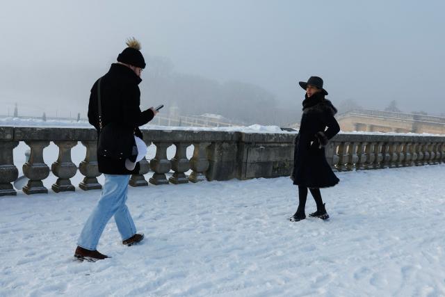 Visitors walk in the snow-blanketed gardens of Versailles outside Paris on January 6, 2026. Some of the winter's coldest weather so far hit travel in Britain, France and the Netherlands on January 5, closing roads, grounding flights and forcing train cancellations, including on Eurostar, just days after a power outage caused major disruption. (Photo by GEOFFROY VAN DER HASSELT / AFP)