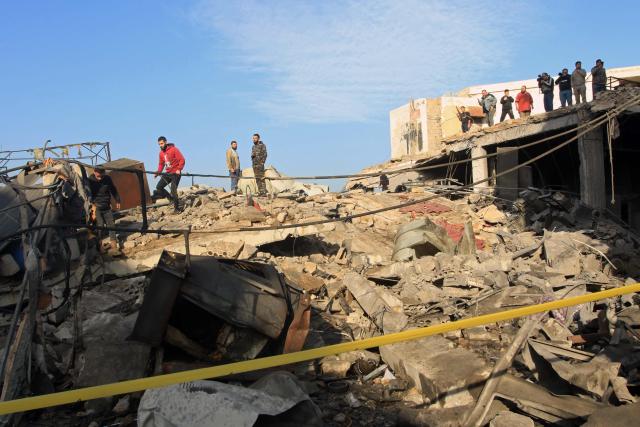 People stand at the site of a building that was destroyed by the Israeli strike in the industrial area of Ghazieh town, near the coastal city of Sidon, in southern Lebanon on January 6, 2026. The Israeli military launched strikes on southern and eastern Lebanon on January 5, 2026, Lebanese state media reported, after warning it would hit what it called Hezbollah and Hamas targets in four villages. It was the first such warning issued by the Israeli military this year, as Israel continues to strike targets in Lebanon despite a ceasefire with Hezbollah. (Photo by Mahmoud ZAYYAT / AFP)