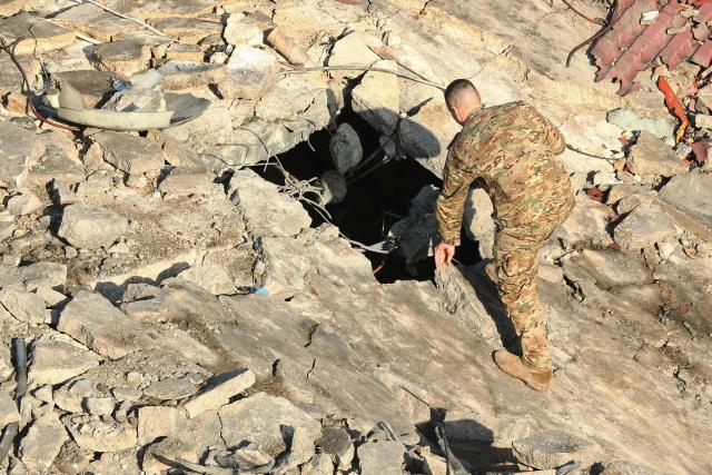 A security personnel inspects the site of a building that was destroyed by the Israeli strike in the industrial area of Ghazieh town, near the coastal city of Sidon, in southern Lebanon on January 6, 2026. The Israeli military launched strikes on southern and eastern Lebanon on January 5, 2026, Lebanese state media reported, after warning it would hit what it called Hezbollah and Hamas targets in four villages. It was the first such warning issued by the Israeli military this year, as Israel continues to strike targets in Lebanon despite a ceasefire with Hezbollah. (Photo by MAHMOUD ZAYYAT / AFP)