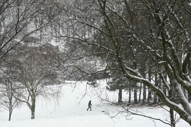 A man walks across a snow-covered golf course near the town of Glossop, Derbyshire, northern England on January 6, 2026, after a light snow covered the region overnight. The UK's Met Office issued fresh weather warnings for January 5-6 for snow and ice for Scotland, Northern Ireland and parts of northern England and said cold weather health alerts for all English regions would remain in place until January 9. (Photo by Oli SCARFF / AFP)