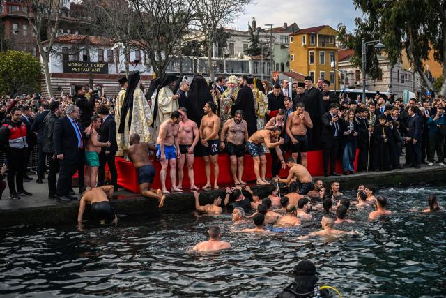 Greek Orthodox faithful climb onto a quayside after swimming to retrieve a wooden cross from the waters of The Golden Horn during a ritual to mark the Epiphany Day in Istanbul on January 6, 2026. (Photo by Ozan KOSE / AFP)