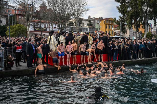Greek Orthodox faithful climb onto a quayside after swimming to retrieve a wooden cross from the waters of The Golden Horn during a ritual to mark the Epiphany Day in Istanbul on January 6, 2026. (Photo by Ozan KOSE / AFP)