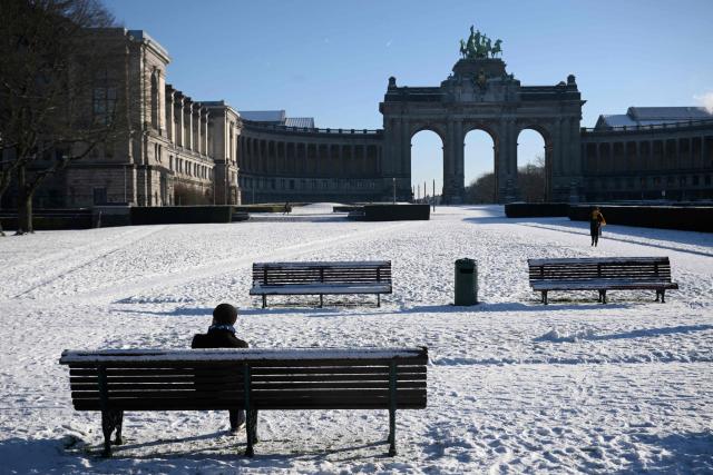 A man sits on a bench in the snow-covered Parc du Cinquantenaire in Brussels, on January 6, 2026. (Photo by Nicolas TUCAT / AFP)