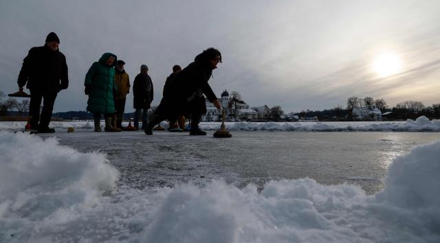 People do curling on the frozen lake "Klostersee" in front of Seeon Abbey, venue of Bavaria's conservative Christian Social Union (CSU) party's faction retreat, in Seeon, southern Germany, on January 6, 2026. (Photo by Michaela STACHE / AFP)