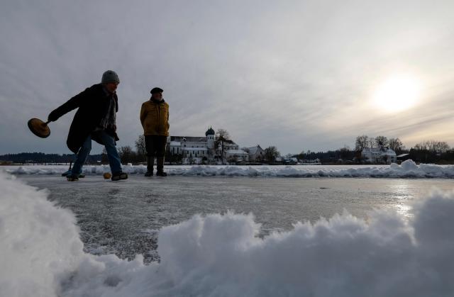 People do curling on the frozen lake "Klostersee" in front of Seeon Abbey, venue of Bavaria's conservative Christian Social Union (CSU) party's faction retreat, in Seeon, southern Germany, on January 6, 2026. (Photo by Michaela STACHE / AFP)