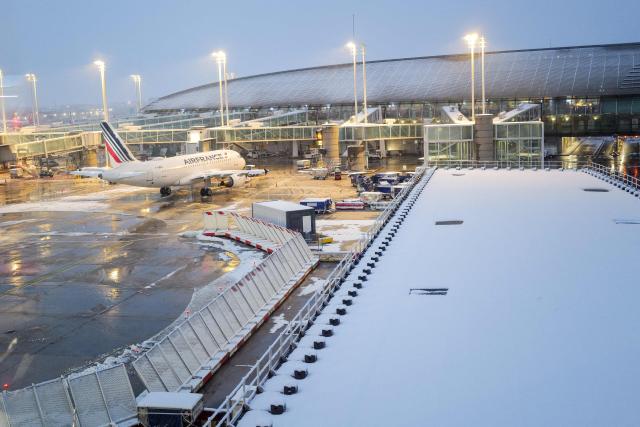 (FILES) This photograph shows an Air France aircraft with snow on the tarmac at the Roissy-Charles de Gaulle airport in Roissy-en-France, in the northern outskirts of Paris, on November 21, 2024. 40% of flights are expected to be cancelled at Paris-Charles-de-Gaulle (CDG) airport and 25% at Orly airport on January 7, 2026 as snow disrupts air, rail and road traffic across the country, French Transport Minister announced. (Photo by Valery HACHE / AFP)
