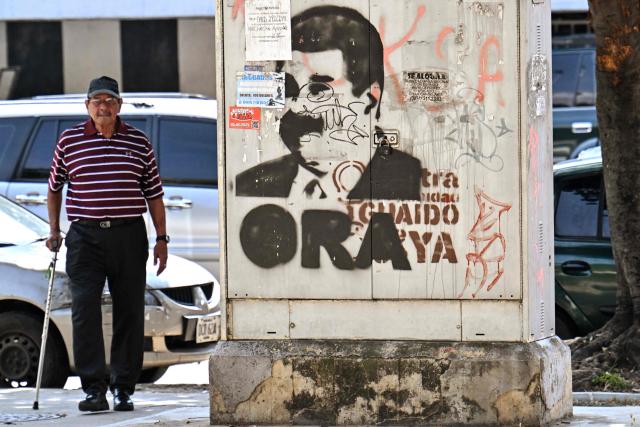 A man walks next to a graffiti of ousted Venezuela's President Nicolas Maduro in Caracas on January 6, 2026. US forces killed 55 Venezuelan and Cuban military personnel during their stunning raid to capture Nicolas Maduro, tolls published by Caracas and Havana showed January 6. (Photo by Juan BARRETO / AFP)