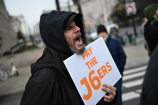 A demonstrator holds a sign as he attends a rally promoted by right-wing activists on the fifth anniversary of the January 6 riots in Washington, DC, on January 6, 2026. Washington on Tuesday marks five years since a mob overran the US Capitol, with rioters pardoned by Donald Trump retracing their steps even as Democrats revive hearings to hold the president accountable. The anniversary highlights a nation divided between irreconcilable accounts of an attack that reshaped American politics -- one supported by official findings of a violent bid to overturn an election, the other portraying it as a protest unjustly criminalized. (Photo by Brendan SMIALOWSKI / AFP)