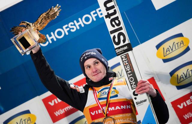 Overall winner Slovenia's Domen Prevc celebrates with the trophy on the podium after the Men's Individual Large Hill HS142 event of the FIS Ski Jumping World Cup, the fourth and last leg of the Four Hills Tournament, in Bischofshofen, Austria on January 6, 2026. (Photo by GEORG HOCHMUTH / APA / AFP) / Austria OUT