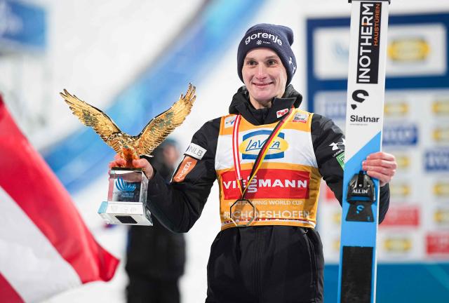 Overall winner Slovenia's Domen Prevc celebrates with the trophy on the podium after the Men's Individual Large Hill HS142 event of the FIS Ski Jumping World Cup, the fourth and last leg of the Four Hills Tournament, in Bischofshofen, Austria on January 6, 2026. (Photo by GEORG HOCHMUTH / APA / AFP) / Austria OUT