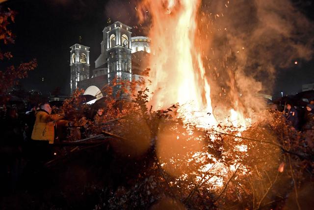Montenegrin Orthodox Christians, throw oak branches on a bonfire after Christmas Eve mass, at the Church of "The Resurection of Jesus Christ", in Podgorica on January 6, 2026. Orthodox Christian believers in Montenegro, observe Christmas in accordance with old "Julian" calendar. (Photo by SAVO PRELEVIC / AFP)