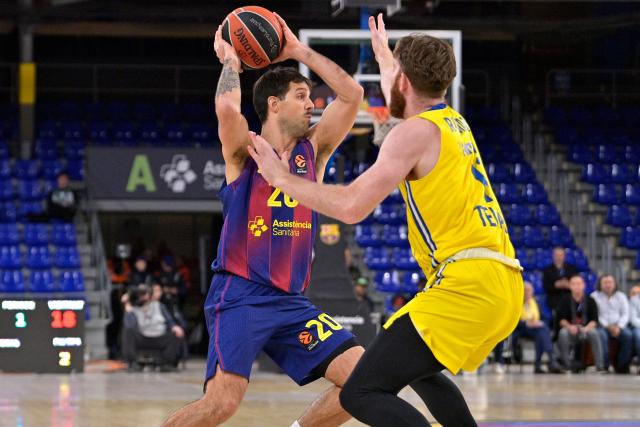 Barcelona's Argentinian guard #20 Nicolas Laprovittola is defended by Maccabi's Israeli forward #11 William Rayman during the closed-door Euroleague basketball match between Barcelona and Maccabi Tel Aviv at Palau Blaugrana arena in Barcelona on January 6, 2026. (Photo by MANAURE QUINTERO / AFP)