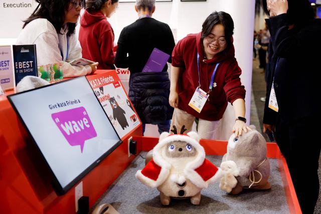 Attendees look at SwitchBot’s KATA Friends, AI companions with a camera nose that is designed to interact with users through voice, gestures, and cloud AI, at the annual Consumer Electronics Show (CES) in Las Vegas, Nevada, on January 6, 2026. (Photo by Caroline Brehman / AFP)