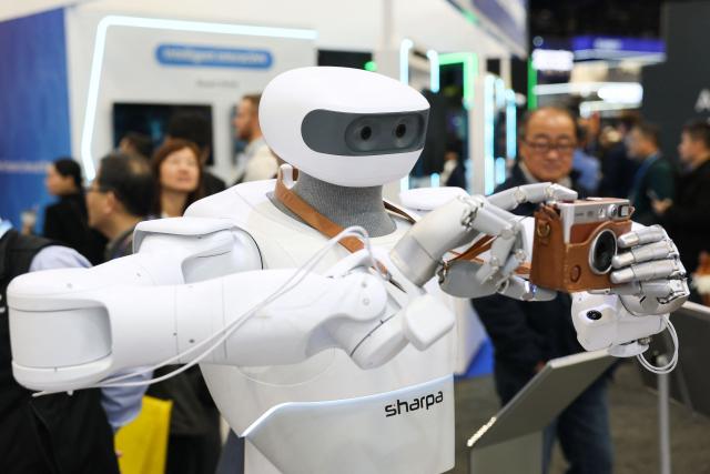 The Sharpa robot takes a photograph with a Fujifilm instax camera during the annual Consumer Electronics Show (CES) in Las Vegas, Nevada on January 6, 2026. (Photo by Patrick T. Fallon / AFP)