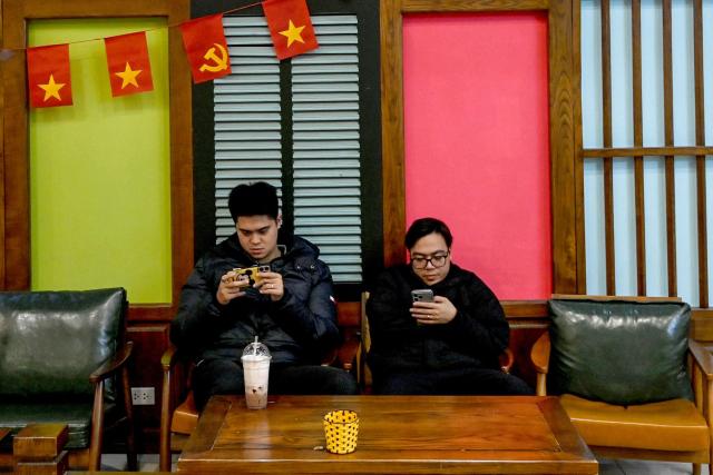 Men use their phones at a cafe in Hanoi on January 7, 2026. (Photo by Nhac NGUYEN / AFP)