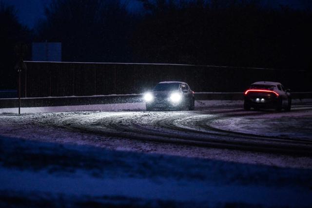 Cars drive along a road as snow falls in Lisieux, northwestern France, on January 7, 2026. Snow and ice are affecting northern and western France, a phenomenon of “rare magnitude in the current climate” according to Meteo-France, which is expected to cause significant restrictions on roads and air transport. (Photo by Lou BENOIST / AFP)