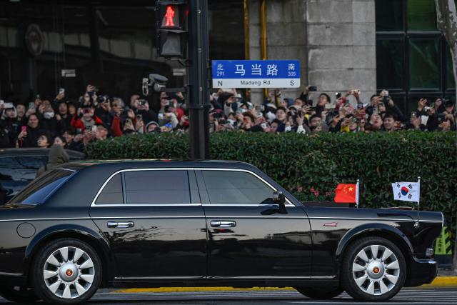 A car with the national flags of China and South Korea leaves after South Korea's President Lee Jae Myung visited the former site of Korea's provisional government, which served as the temporary government of Korea during Japan's colonial rule, in Shanghai on January 7, 2026. South Korean President Lee Jae Myung said on January 7, he had urged Chinese leader Xi Jinping to help him curb Pyongyang's nuclear programme and suggested a freeze in its development of weapons of mass destruction was "feasible" with the right conditions. (Photo by Jade GAO / AFP)