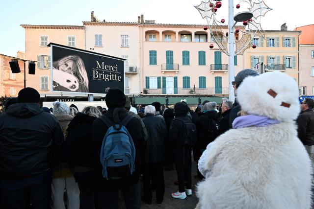 Mourners and fans wait to watch on a screen the live broadcast of the funeral ceremony for late French actress Brigitte Bardot, at Notre-Dame de l'Assomption church in Saint-Tropez, southeastern France, on January 7, 2026. French film sensation Brigitte Bardot, a symbol of sexual liberation in the 1950s and 1960s who reinvented herself as an animal rights defender and embraced far-right views, died on Decmber 28, 2025 aged 91. (Photo by Miguel MEDINA / AFP)