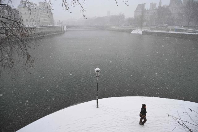 TOPSHOT - This photograph shows a view of the Seine river and its snow-covered banks during heavy snow falls, in Paris on January 7, 2026. Snow and ice are affecting northern and western France, a phenomenon of “rare magnitude in the current climate” according to Meteo-France, which is expected to cause significant restrictions on roads and air transport. (Photo by Bertrand GUAY / AFP)
