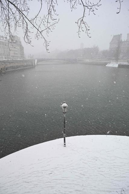 This photograph shows a view of the Seine river and its snow-covered banks during heavy snow falls, in Paris on January 7, 2026. Snow and ice are affecting northern and western France, a phenomenon of “rare magnitude in the current climate” according to Meteo-France, which is expected to cause significant restrictions on roads and air transport. (Photo by Bertrand GUAY / AFP)
