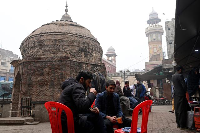Locals drink tea on a cold winter morning in Lahore on January 7, 2026. (Photo by Arif ALI / AFP)