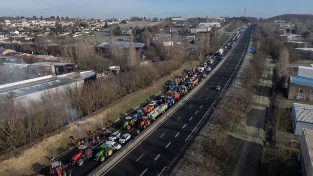 Traffic backs up on the A63 highway behind farmers protesting to defend their profession and denounce the government's handling of the agricultural crisis, outside Toulouse on January 7, 2026. Using tractors, bales of straw, and manure, farmers erected a dozen roadblocks on the main roads around Toulouse, despite a significant deployment of law enforcement, with the aim of “paralyzing” the city to defend their profession in the midst of a crisis. (Photo by Ed JONES / AFP)