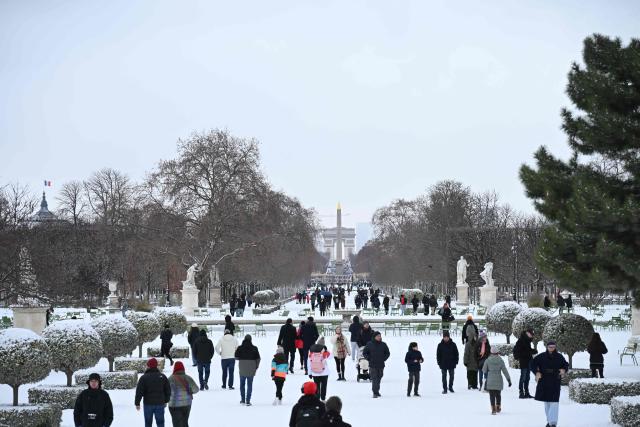 People walk in the Jardin des Tuileries gardens after heavy snowfalls in central Paris on January 7, 2026. Snow and ice are affecting northern and western France, a phenomenon of “rare magnitude in the current climate” according to Meteo-France, which is expected to cause significant restrictions on roads and air transport. (Photo by Bertrand GUAY / AFP)