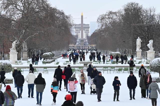 People walk in the Jardin des Tuileries gardens after heavy snowfalls in central Paris on January 7, 2026. Snow and ice are affecting northern and western France, a phenomenon of “rare magnitude in the current climate” according to Meteo-France, which is expected to cause significant restrictions on roads and air transport. (Photo by Bertrand GUAY / AFP)