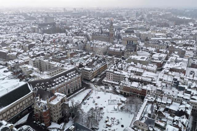 An aerial view shows the Place Rihour (Foreground), the Ferris Wheel and the Chamber of Commerce Bell Tower in downton Lille, northen France, following a fresh snowfall on January 7, 2026. (Photo by Anthony Brzeski / AFP)