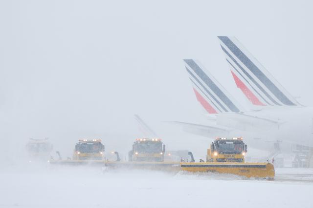 Air France airplanes are seen on the tarmac as snowplows clear the runways after heavy snowfalls, which caused flight cancellations at Orly Airport, south of Paris on January 7, 2026. Around 100 flights were cancelled at Paris's Charles de Gaulle airport because of snowfall and fierce cold, and a further 40 were cancelled at Orly airport, France's transport minister said. (Photo by Kiran RIDLEY / AFP)