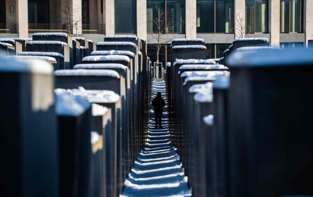 A visitor walks through the snow-covered steles of the Holocaust memorial in Berlin on January 7, 2026 following abundant snow fall and sub-zero temperatures in the capital. (Photo by John MACDOUGALL / AFP)