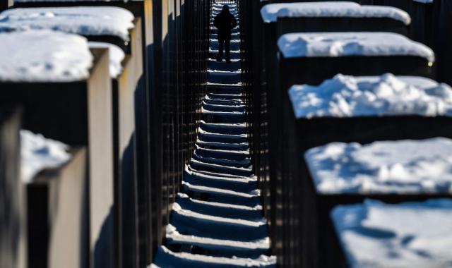 A visitor walks through the snow-covered steles of the Holocaust memorial in Berlin on January 7, 2026 following abundant snow fall and sub-zero temperatures in the capital. (Photo by John MACDOUGALL / AFP)