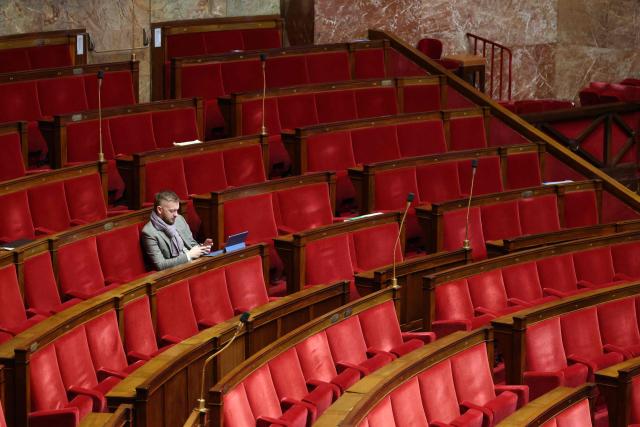 Rassemblement National's MP Kevin Pfeffer uses a smartphone surrounded by empty seats as attends a session of questions to the government at The National Assembly, France's lower house parliament in Paris on January 7, 2026. (Photo by Ludovic MARIN / AFP)