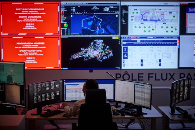 Airport staff monitor screens during a blizzard at Orly Airport, south of Paris on January 7, 2026. Around 100 flights were cancelled at Paris's Charles de Gaulle Airport because of snowfall and fierce cold, and a further 40 were cancelled at Orly Airport, France's transport minister said. (Photo by Kiran RIDLEY / AFP)